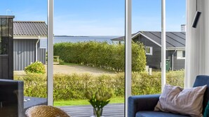 Habitación moderna con ventanas amplias que dan a un jardín y una masa de agua.