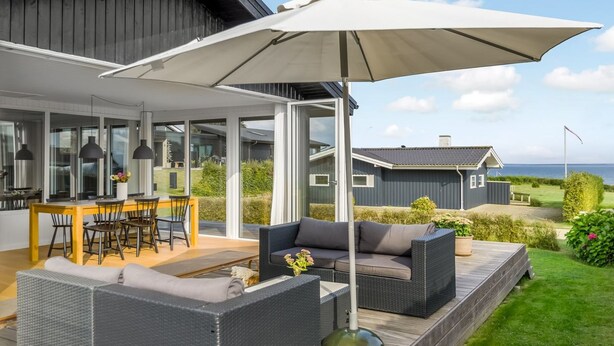 Un espacio exterior moderno con mesa de comedor, sillas y sofá.
