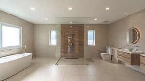 Ein modernes Badezimmer mit freistehender Badewanne, einer begehbaren Duschkabine und einem Waschtisch mit Spiegel.