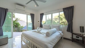 Ein Hotelzimmer mit einem Bett, einem Deckenventilator, einem Fenster mit Vorhängen und Blick ins Freie.