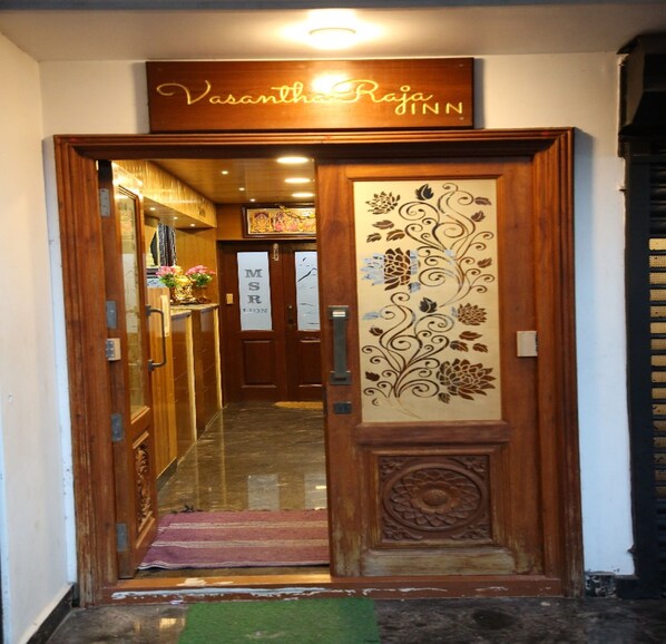 A wooden entrance with a sign reading "Vasantha Raja Inn".