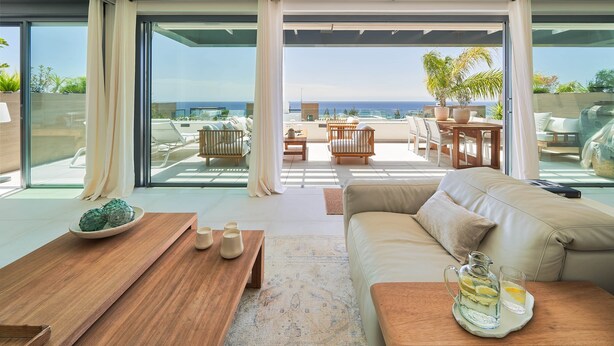 Ein modernes Wohnzimmer mit einer Couch, einem Couchtisch und Meerblick durch große Fenster.