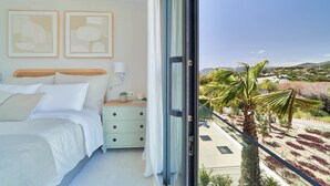 Ein Schlafzimmer mit Bett, Nachttisch und Blick auf einen angelegten Garten.