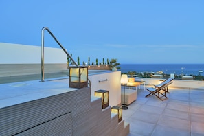 A rooftop terrace with a pool, seating area, and a view of the ocean.