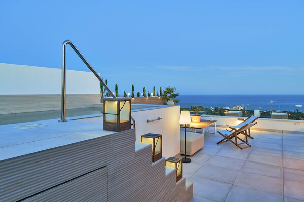 A rooftop terrace with a pool, seating area, and a view of the ocean.