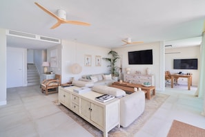 A spacious living room with a sofa, a coffee table, a TV, and a staircase leading to another room.