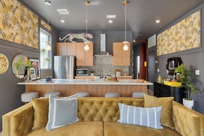 Una cucina moderna con isola centrale, illuminazione a sospensione e un elemento decorativo a parete.