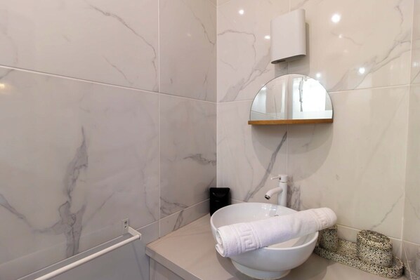 Une salle de bain avec un lavabo en marbre blanc, un miroir rond et un porte-serviettes.