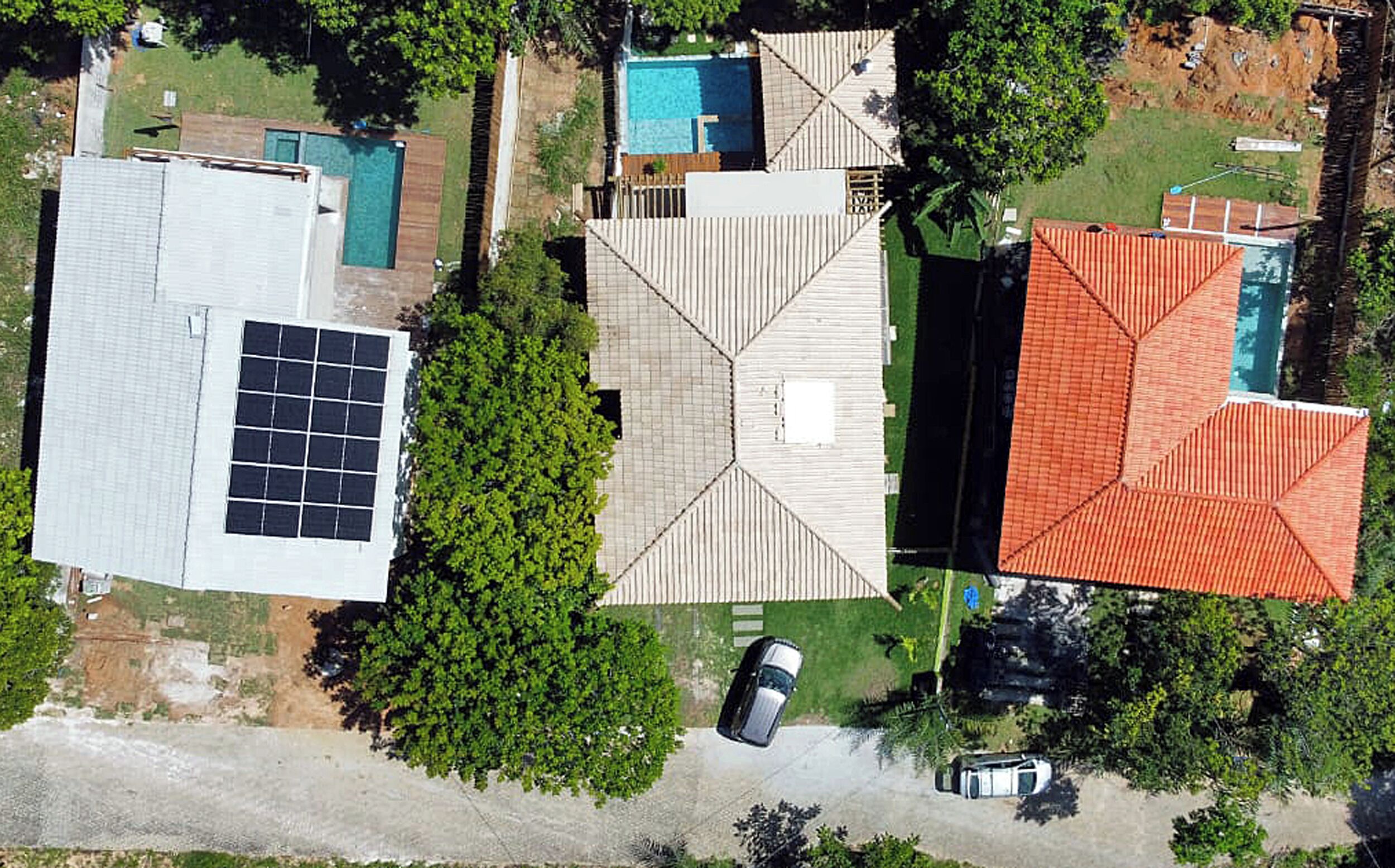 A residential area with multiple houses, a swimming pool, and a solar panel installation.