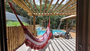 A hammock, pool, and outdoor seating area on a wooden deck.