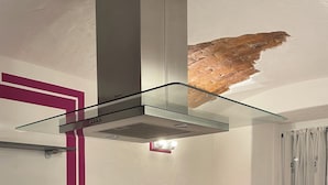 Una cuina moderna amb fogó de vitroceràmica, campana extractora d'acer inoxidable i electrodomèstics integrats.
