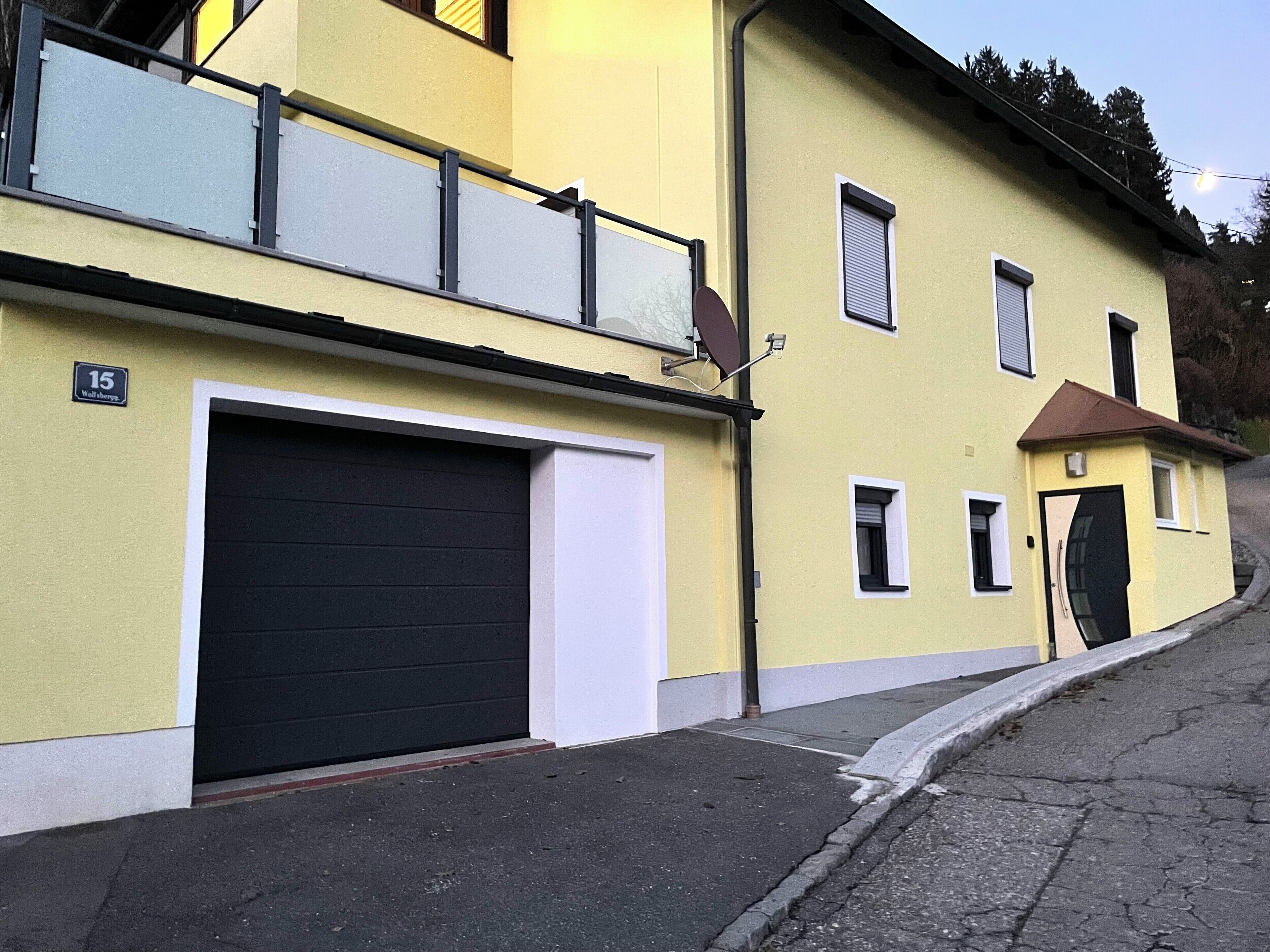 Ein gelbes Gebäude mit einer Garagentür, einem kleinen Fenster und einem Schild mit der Nummer 15.