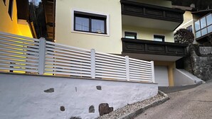 Un edifici modern amb façana blanca, base de pedra i tanca metàl·lica.
