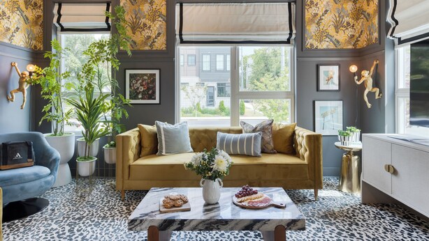 Un salon confortable avec un canapé, une table basse sur laquelle sont disposés des en-cas et une grande fenêtre donnant sur l’extérieur.