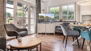 A modern living room with a TV, seating, and a dining area. - Apartment 50091 - Completely balanced: The first floor apartment is located in (Wittmund)