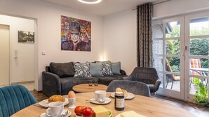 A cozy living room with a sofa, a coffee table with breakfast items, and a large window with curtains. - Apartment 50091 - Completely balanced: The first floor apartment is located in (Wittmund)