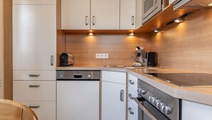 A compact kitchen with white cabinets, a Bosch dishwasher, a stove, and a microwave. - Apartment 50091 - Completely balanced: The first floor apartment is located in (Wittmund)