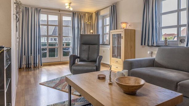 Un salon moderne comprenant un canapé, un fauteuil, une table basse en bois et un meuble de rangement.