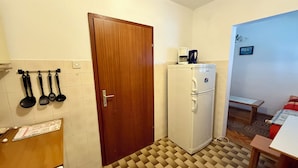 Una cocina compacta con refrigerador, cafetera y mesa de comedor.