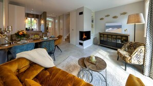A modern living room with a fireplace, a dining area, and a sofa. - Haus Sylter Schönheit - Welcome to Sylter Schönheit. (Sylt Westerland)