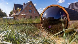 A house with a large circular structure in front, surrounded by grass. - Haus Sylter Schönheit - Welcome to Sylter Schönheit. (Sylt Westerland)