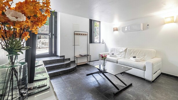 Un salon moderne avec un canapé blanc, une table basse en verre et un vase de fleurs.