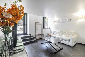 En moderne stue med en hvid sofa, et glasbord og en vase med blomster.