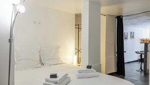 Une chambre d’hôtel avec un lit, des serviettes, une lampe, un bureau et une chaise.