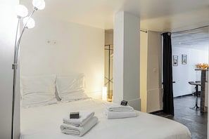 A hotel room with a bed, towels, a lamp, a desk, and a chair.