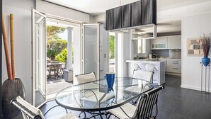 A modern kitchen with a central island, a glass dining table, and a view of the outdoors.