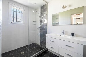 A modern bathroom with a shower, a sink, and a mirror.