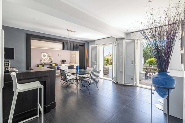 A modern kitchen with a dining area, a bar counter, and a large window.