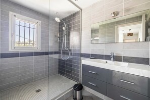 A modern bathroom with a shower, a sink, and a mirror.