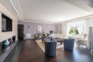Un salon moderne avec une cheminée, un ensemble de canapés, une table basse et une vue sur l’extérieur.