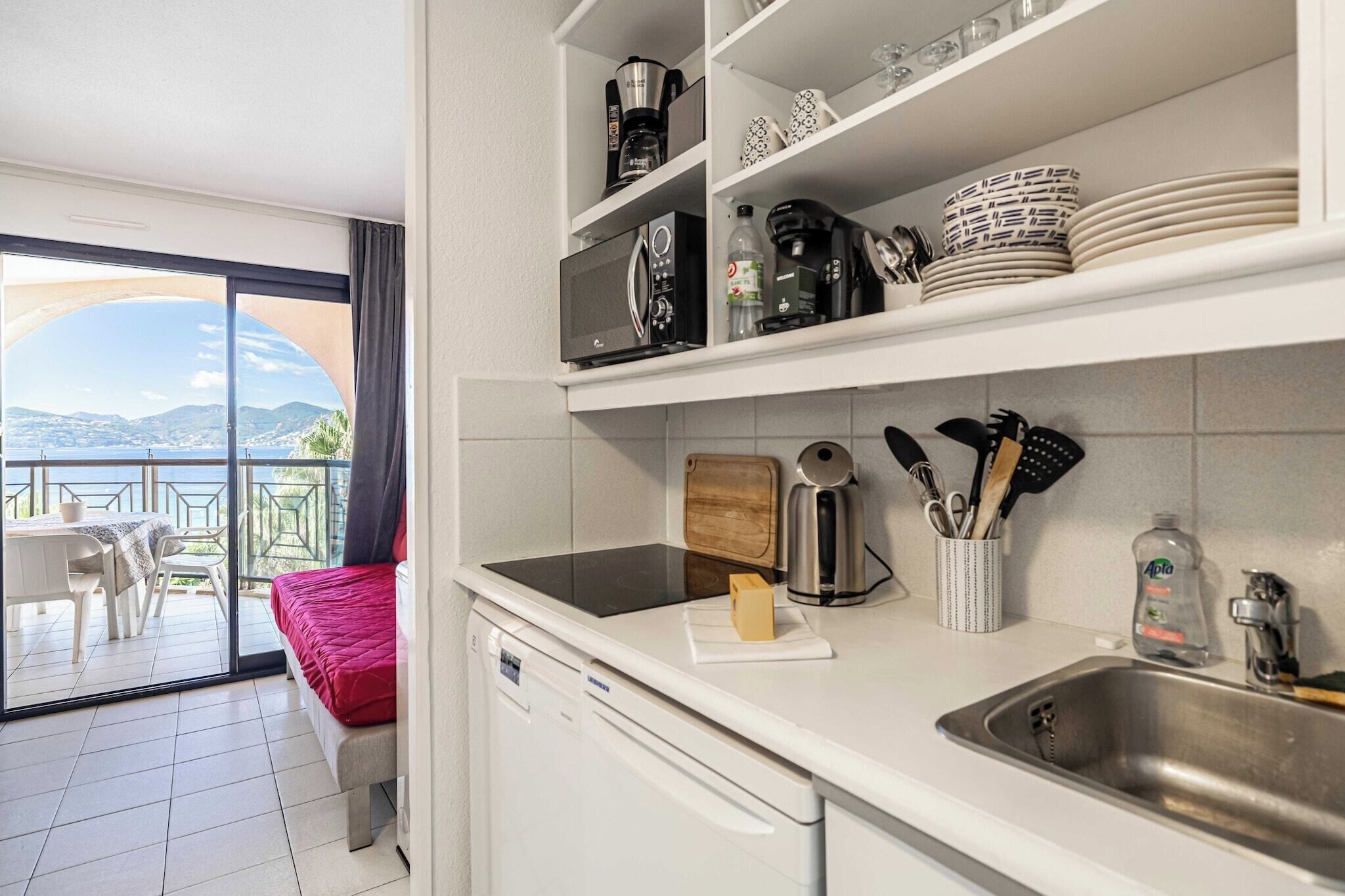 Una cucina moderna con lavastoviglie, macchina da caffè e lavello. Un balcone con tavolo e sedie offre vista sulle montagne.