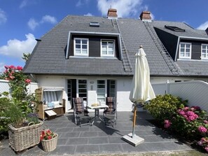 A house with a sloped roof, a patio with outdoor furniture, and a white umbrella.