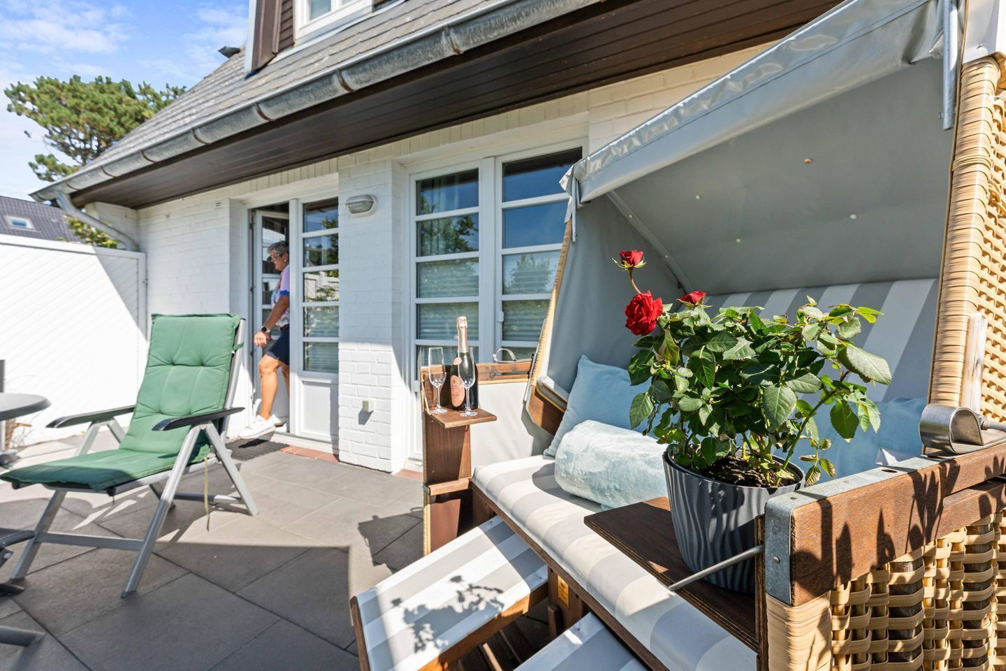 A patio with outdoor furniture, a potted plant, and a bottle of champagne.