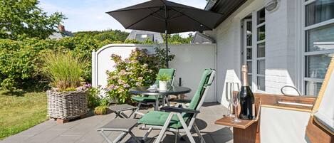 Un patio al aire libre con una mesa, sillas y una sombrilla.