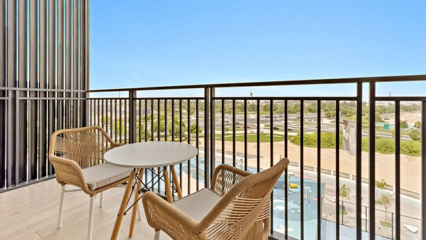A balcony with wicker furniture and a view of a cityscape.