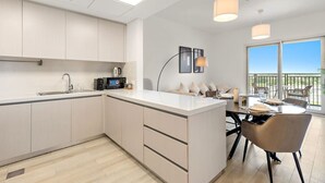 A modern kitchen with a central island, a dining area with a view, and a balcony with outdoor seating.