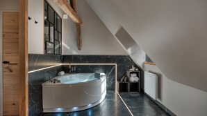 A modern bathroom with a freestanding bathtub, marble walls, and exposed wooden beams. - The splendid Collégiale Saint André (Chartres)