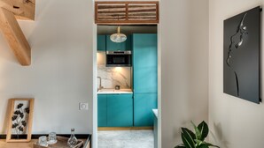 A modern kitchen with teal cabinets, a marble countertop, and a hanging light fixture. - The splendid Collégiale Saint André (Chartres)