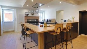 Una cocina moderna con una isla central, taburetes de bar y una mesa de comedor.