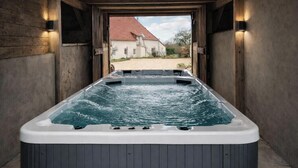 Un jacuzzi con vista a una casa a través de un vano abierto.