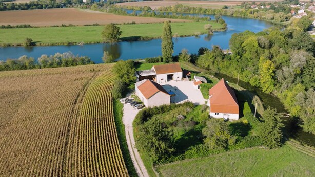 Vista aérea de una propiedad rural con una casa rodeada de campos y un lago.