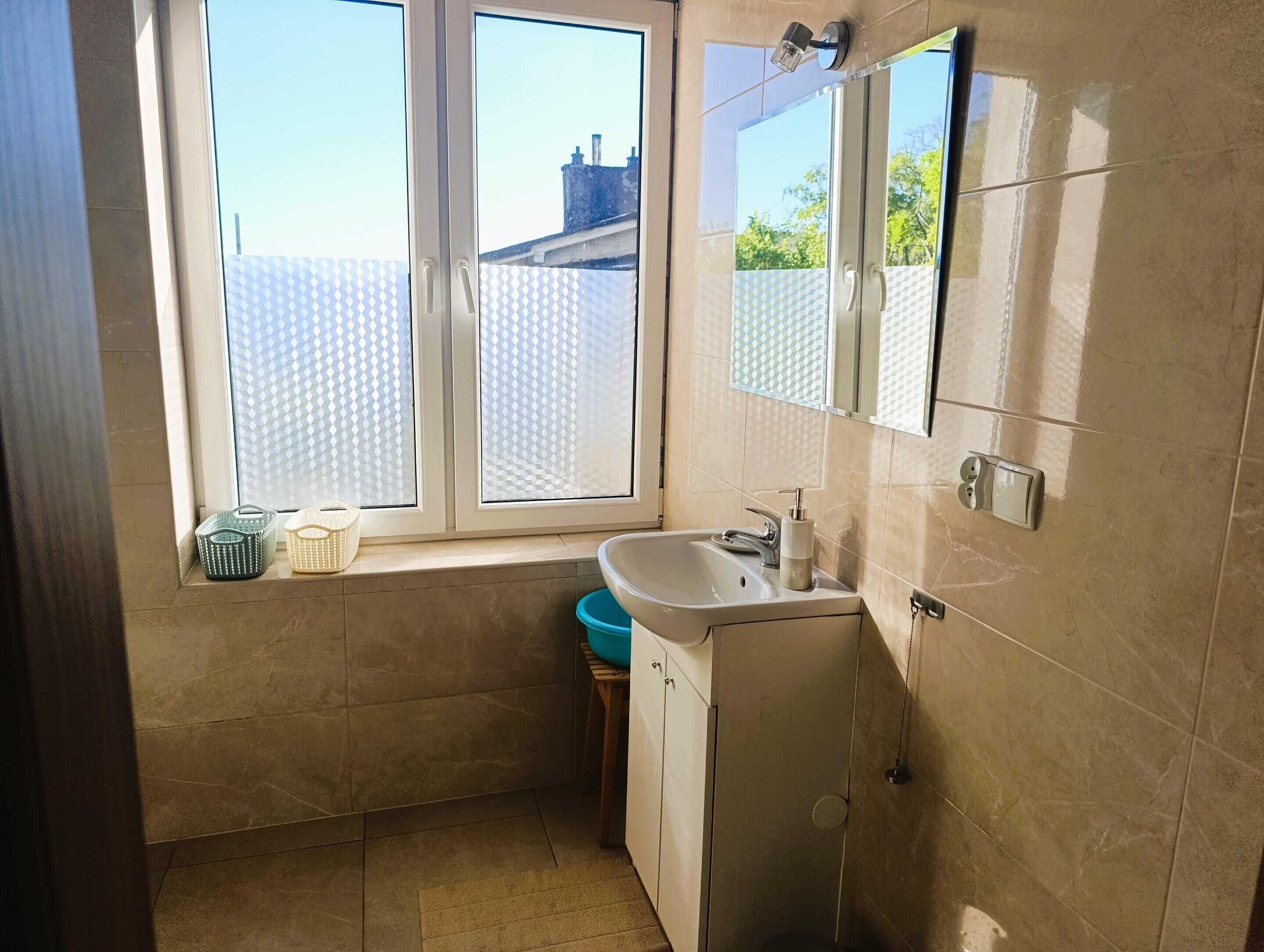 A bathroom with a window, a sink, and a mirror.