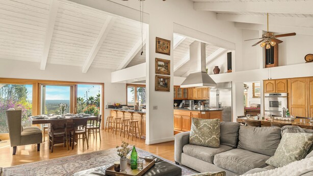 A spacious living area with a dining table, a sofa, and a kitchen in the background. - Resort-Style Estate • Pool + Game Room + Tennis Court | The Tennis Ranch (Escondido)