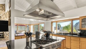 A modern kitchen with a central island, stainless steel appliances, and wooden cabinets. - Resort-Style Estate • Pool + Game Room + Tennis Court | The Tennis Ranch (Escondido)