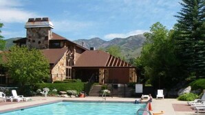 Une piscine avec des chaises longues et un bâtiment en pierre doté d’une cheminée.
