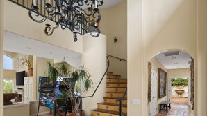 Ein geräumiger Innenraum mit Treppe, einer Kandelaber und einer großen Kübelpflanze.